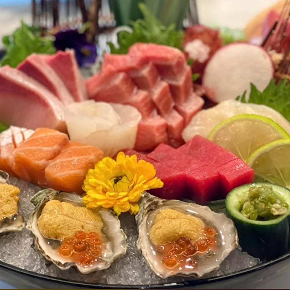 A platter of fresh sashimi, including tuna, salmon, scallops, and oysters with uni and roe.